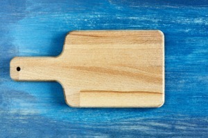 Empty wooden cutting board on rustic blue table.