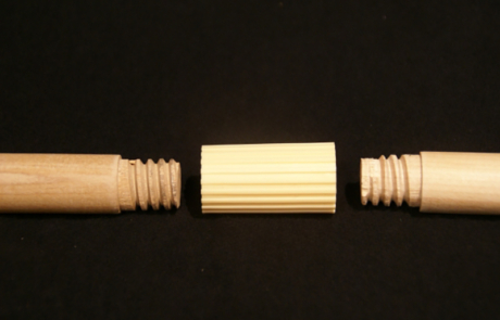 Two wood dowels with threaded ends are screwed together using a plastic connector