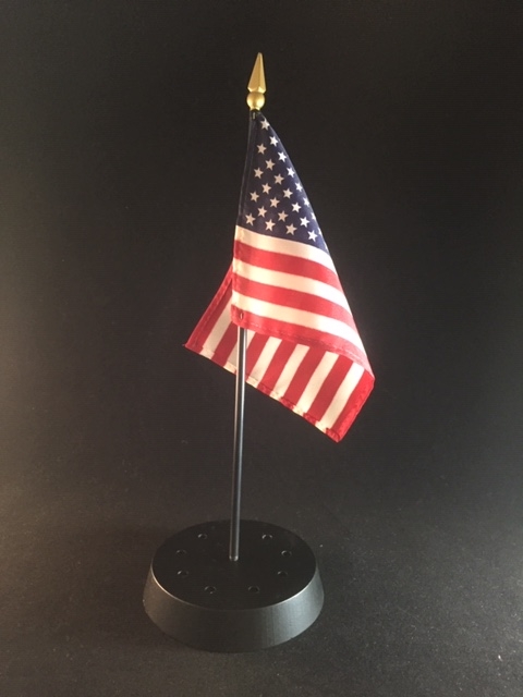 A small round black painted custom wooden flag base drilled with a hole so that the flag can attach to the base.