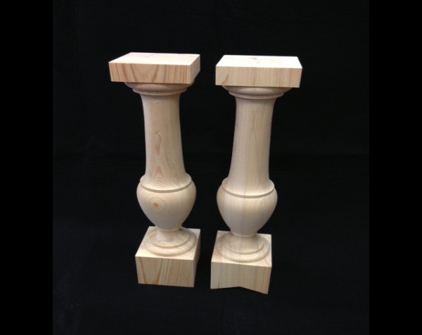 Two large diameter wooden balusters. Both are turned in the middle with square top and bottom. One has a "V" cut on the bottom end.