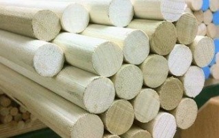 Multiple smooth poplar wood dowels stacked for custom bulk manufacturing projects.