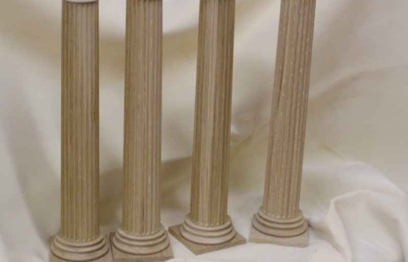 Four white oak wooden columns standing in a row over a draped white background.