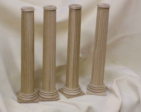 Four white oak wooden columns standing in a row over a draped white background.