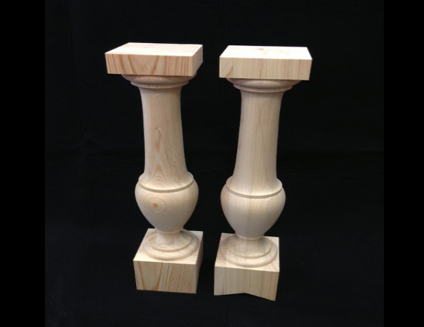 Two large diameter wooden balusters. Both are turned in the middle with square top and bottom. One has a "V" cut on bottom end.