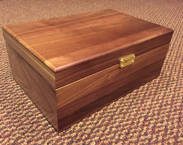 Higher end hinged top custom wood box with front latch. The box is Walnut with a clear finish.