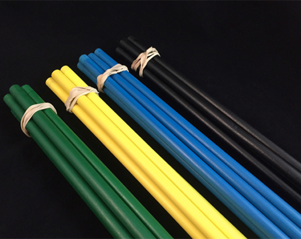 One bundle each of green, yellow, blue and black painted wooden dowels, tied with rubber bands