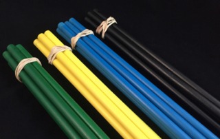 Bundles of green, yellow, blue, and black painted wooden dowels, tied with rubber bands, available in custom sizes and finishes.