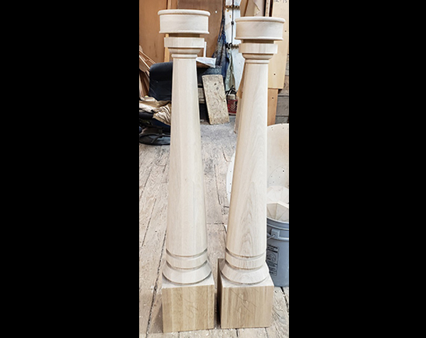 Two wood newel posts that are square on bottom with turned milled and rounded top
