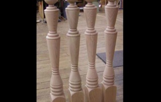 Four turned alder spiral newel posts with a ball top design, crafted for staircases and architectural millwork.