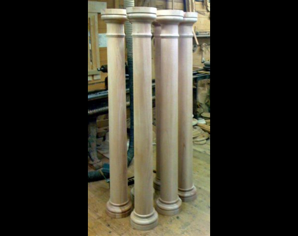 Four larger wood columns with a tapered middle section, capitals and bases