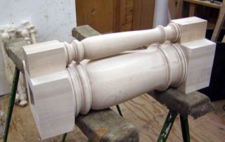 Two short turned wood columns with smooth cylindrical design, laying on their side.
