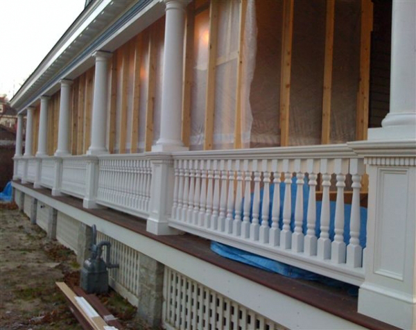 View of house porch with turned white wood balusters and columns and square newels