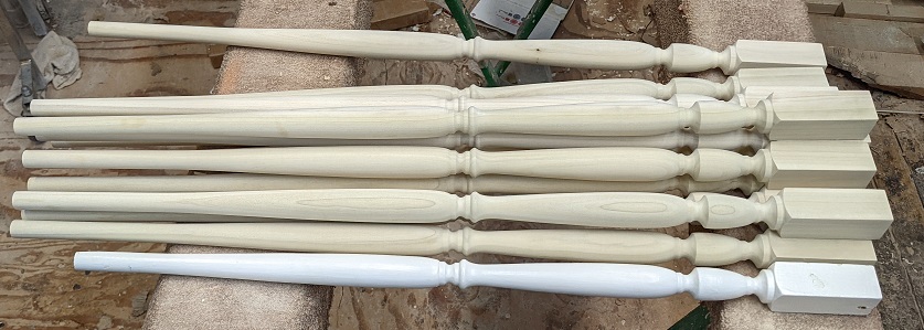 A group of custom Poplar balusters that are matched and compared to a customer sample.