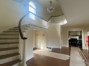 Close-up view of newly installed custom poplar balusters and a newel post on a staircase.