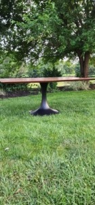 A completed wood dining table base with a smooth painted finish, fully assembled with the matching tabletop.