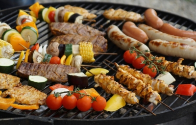 Wooden skewers with meat and vegetables on a grill.