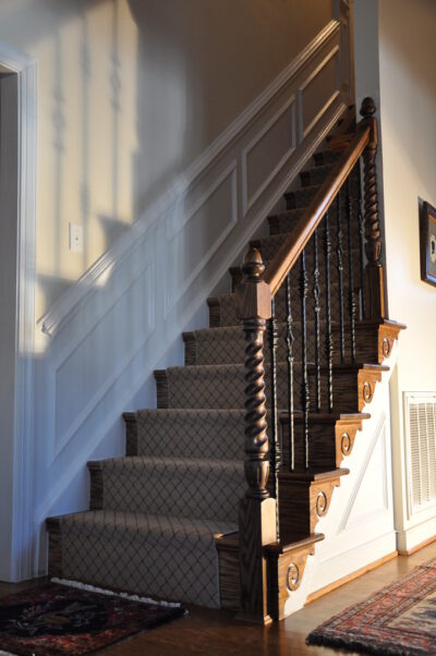 A beautifully crafted wood newel post at the base of a staircase.