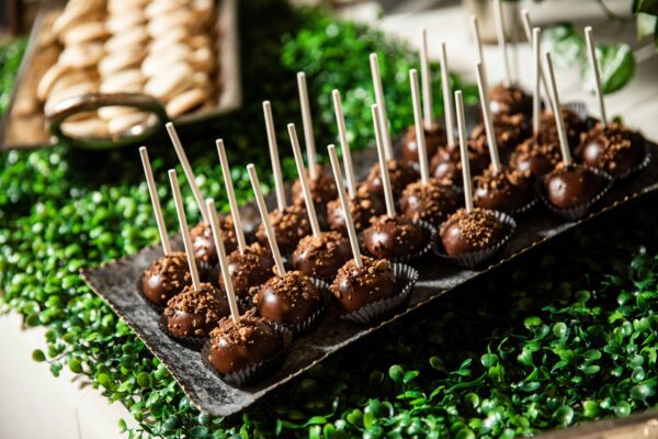 A selection of wedding dessert cake pops with wood sticks for food to serve.