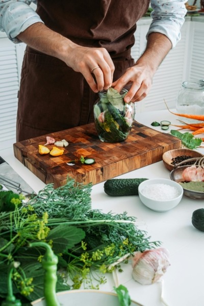 Sanitizing a Wood Cutting Board Person using a wood cutting board to prepare vegetables and herbs for pickling in a home kitchen.
