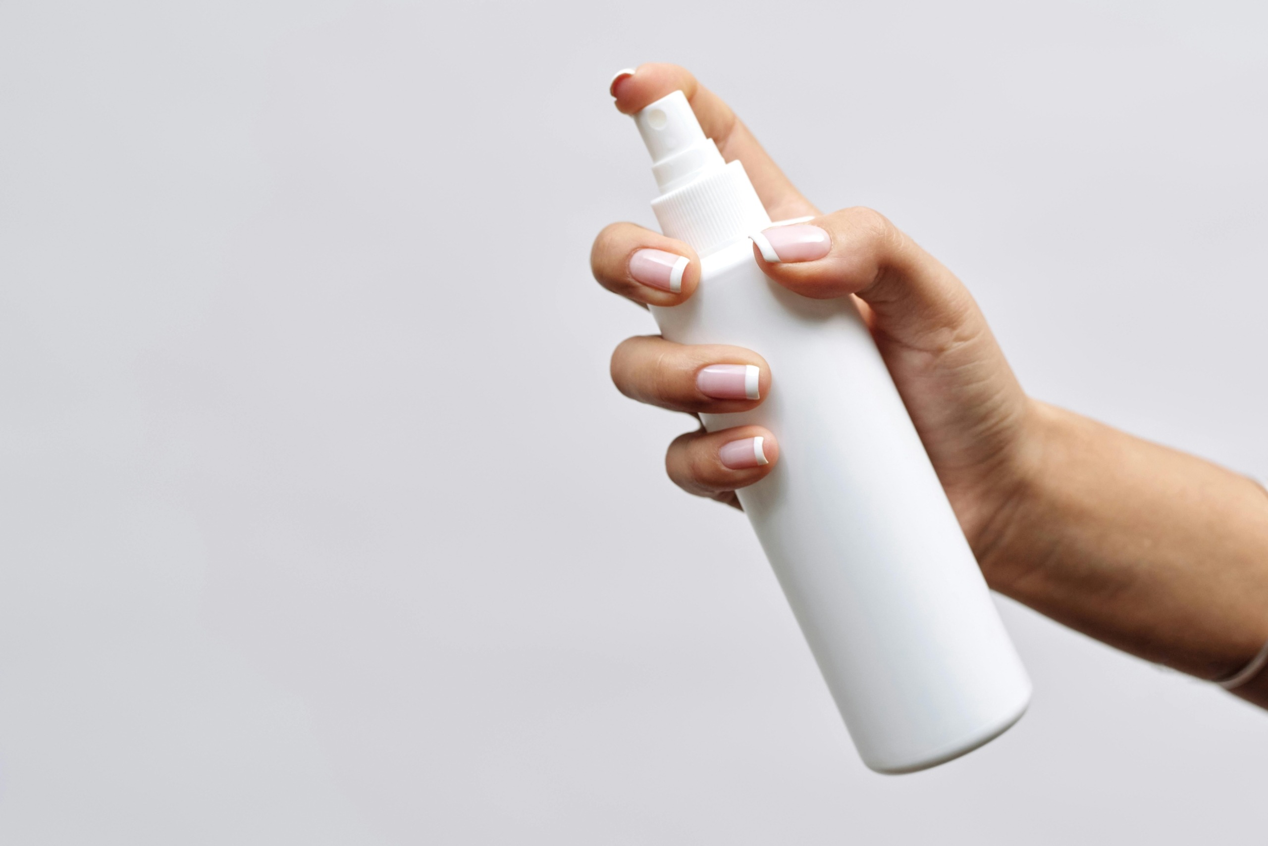 Spray Bottle for Cutting Board Sanitizing Hand holding a white spray bottle used to sanitize wood cutting boards with a vinegar or bleach solution.