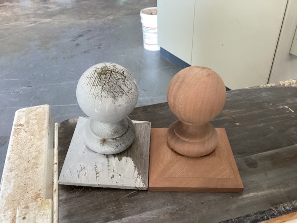 New sapele newel post cap finial next to weathered customer sample on a workbench.