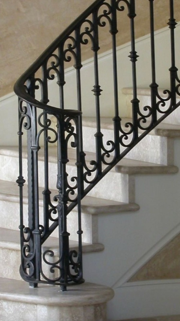Close-up of an ornamental iron staircase railing with scrollwork and decorative balusters.