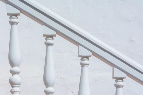 Example of Close-Up of Painted Wood Spindles After Replacement White painted wood spindles installed along a handrail after replacement.