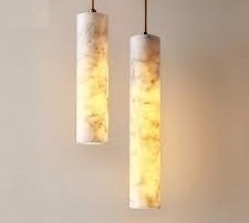A pair of alabaster cylinder pendant lights suspended from the ceiling with warm internal glow.