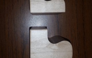 Two interlocking puzzle-shaped lamp base halves CNC machined from soft maple wood.