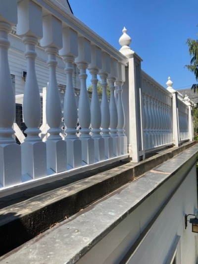 Custom Turned Wood Balusters on Exterior Fence Custom-turned exterior wood balusters installed on a street-level fence railing, showing a second baluster profile on the same residential property