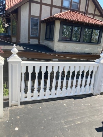 Exterior Wood Balustrade with Turned Post Caps Exterior wood balustrade on a residential balcony showing turned post caps and rail detail, part of a custom mahogany baluster supply project