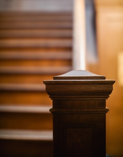 Newel Post at the Bottom of a Staircase Dark stained square wood newel post anchoring the bottom of a staircase